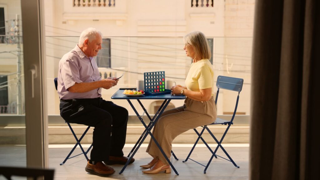 Older couple playing a board game outside their balcony